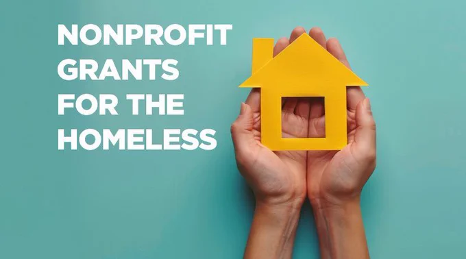 in white letters "nonprofit grants for the homeless", next to a white man's hands holding a yellow cut out of a house