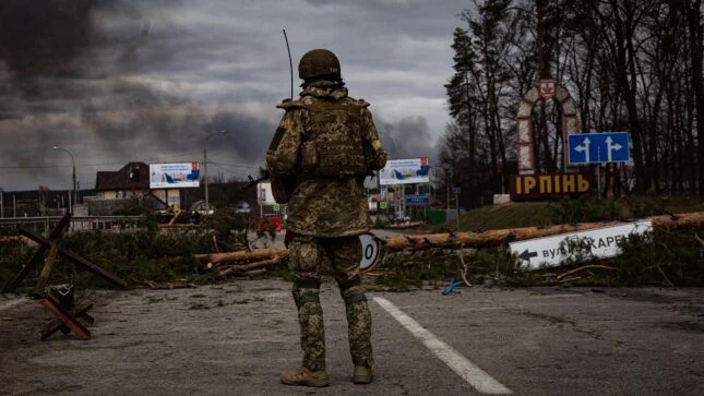 Ukrainian soldier stands on the check point to the city Irpin near Kyiv during the evacuation of local people under the shelling of the Russian troops, courtesy of Kutsenko Volodymyr/Shutterstock.com.