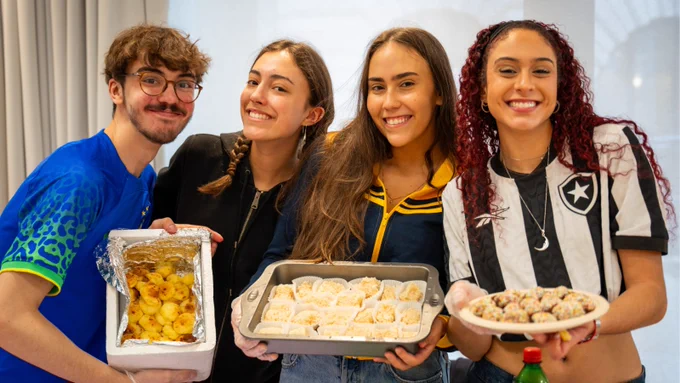 A group of four young adults smiling and holding homemade food.