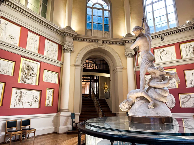 A classical statue surrounded by plaster models in the walls of the circular Flaxman Gallery. 