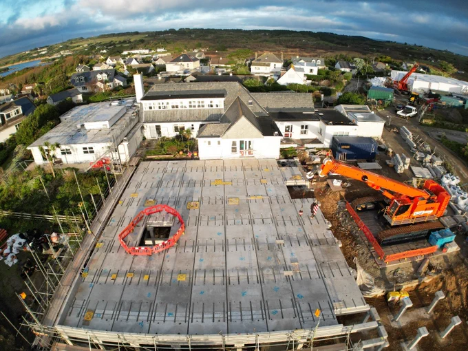 St Mary’s Community Hospital and the construction site for the new Isles of Scilly Integrated Health and Social Care Facility. The foundations are in the foreground. The cranes and modular units are in the background.
