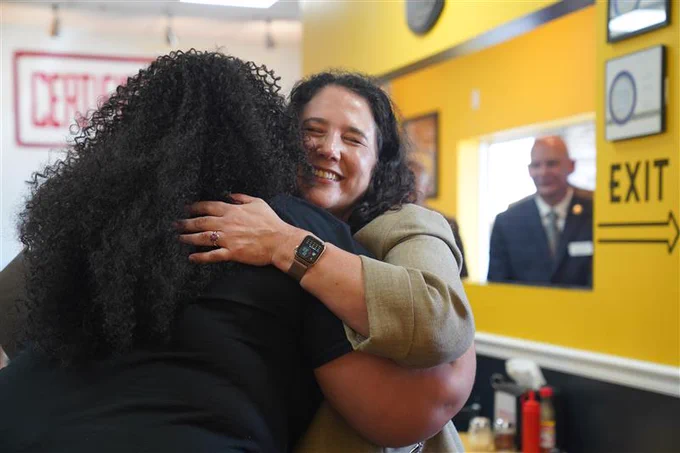 Two individuals warmly embracing in a cheerful room with yellow walls and diner-style decor.