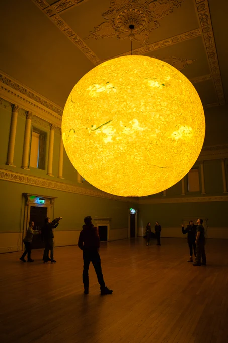 Helios hanging from the Ball Room ceiling with people stood underneath looking up.