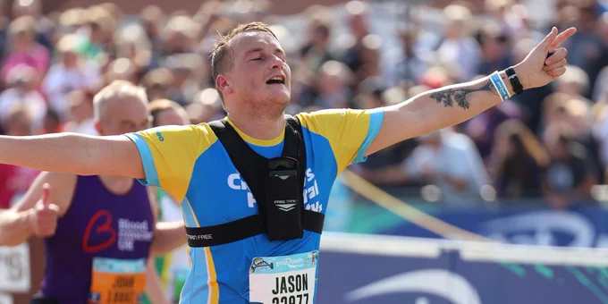 A man runs through a finish line at the Great North Run. 