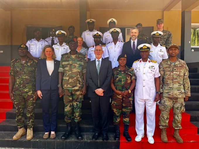 A group of individuals, both military and civilian, staggered on a stairway pose for a photo