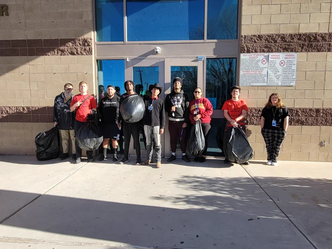 Nine Job Corps students stand with bags of garbage from a community cleanup project.