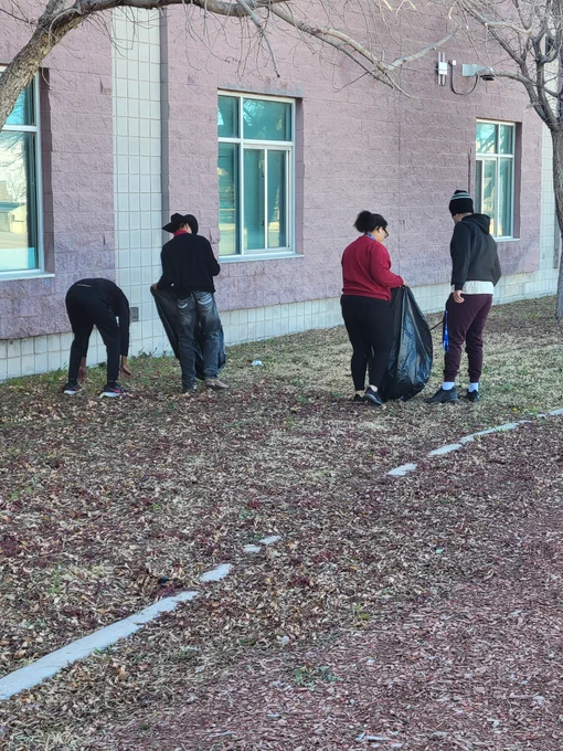 Four students pick up trash during a community cleanup project.