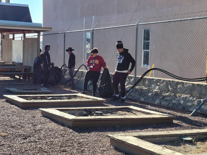 Five students participate in an outdoor community cleanup project.
