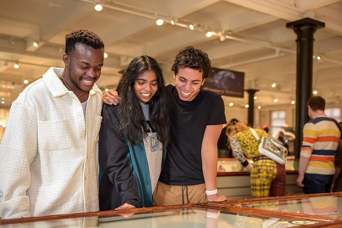 Group of people smiling and looking down at a museum case