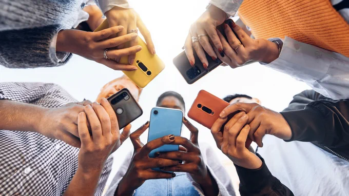 Multicultural group of young people using cell phones outside