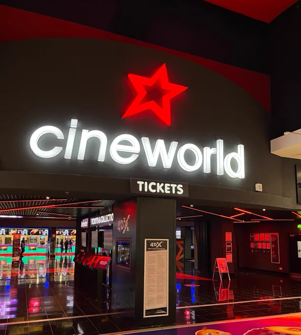 Interior view of a Cineworld cinema lobby featuring a large, illuminated 'Cineworld' sign with a red star above the ticket counter.