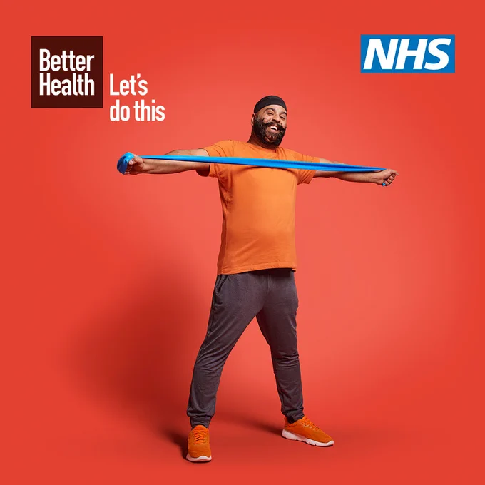 The Better Health Let's do this logo is positioned in the top left corner and the NHS logo is in the top right. The background is red and a man wearing an orange top, dark pants and orange trainers is stood in the centre frame. He is stretching his arms out wide using a blue resistance band.