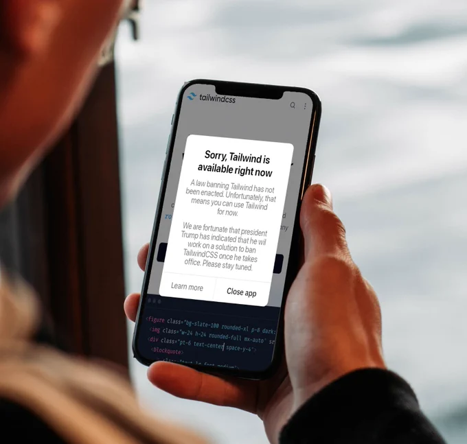 Clearly photoshoped picture of a man holding an iphone with the browser open on the tailwindcss website. There's a popup message that reads: "Sorry, Tailwind is available right now. A law banning Tailwind has not been enacted. Unfortunately, that mens you can use Tailwind for now. We are fortunate that president Trump has indicated he will work on a solution to ban TailwindCSS once he takes office. Please stay tuned."