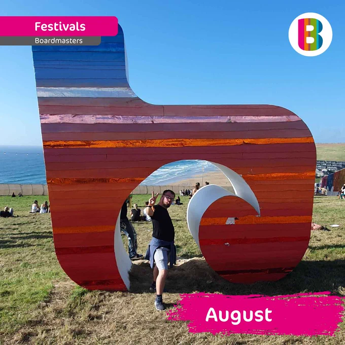 A photo of a young man giving the peace sign in front of a giant cut-out wave in the shape of a B. Includes text: Festivals: Boardmasters