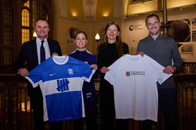 Four people standing next to each other, two holding a Birmingham City Football Club top and two holding a University of Birmingham top
