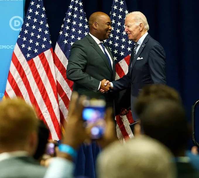 DNC Chair Jaime Harrison shaking hands on stage with President Joe Biden at a DNC event.