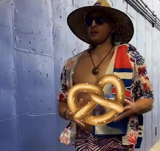 Mack Hollins in tropical garb holding a cartoon giant pretzel