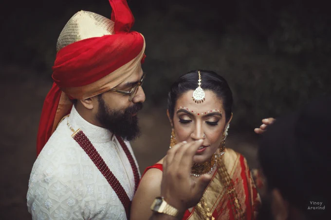 A head-and-shoulders shot of a couple, from overhead, where you can see the hands of another photographer, directing them.