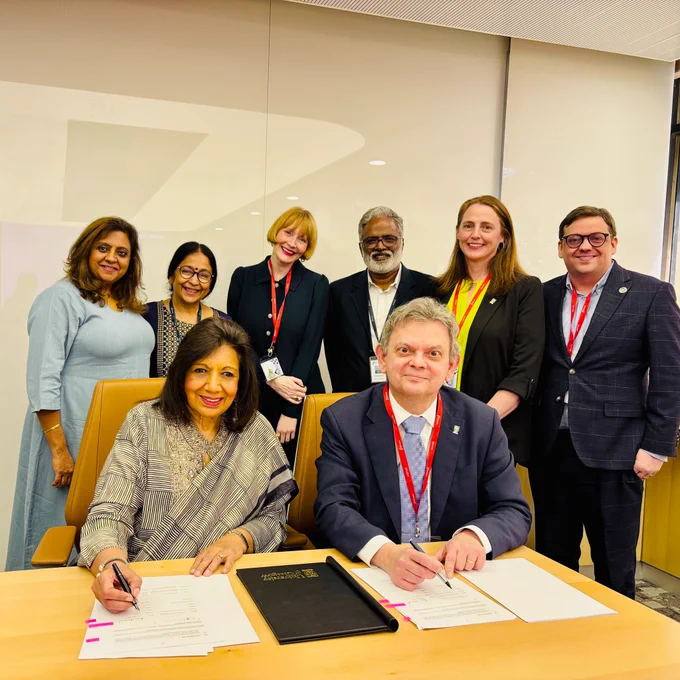 University of Glasgow colleagues on a multi-city delegation to India. People sitting at a desk signing an agreement between the University of Glasgow and Indian biopharmaceutical giant Biocon. 