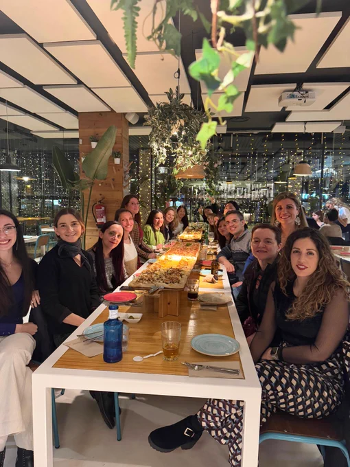 Foto de varias mentoras y mentorizadas en la mesa con una pizza de dos metros.