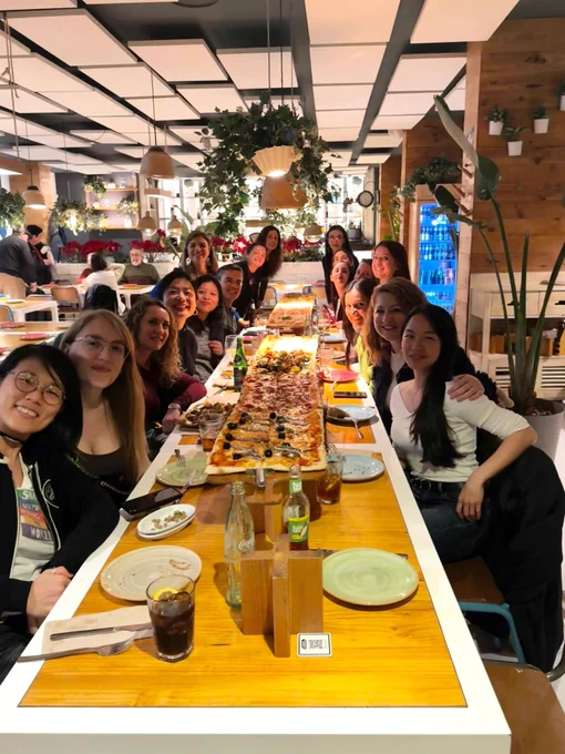 Foto de varias mentoras y mentorizadas en la mesa con una pizza de dos metros.