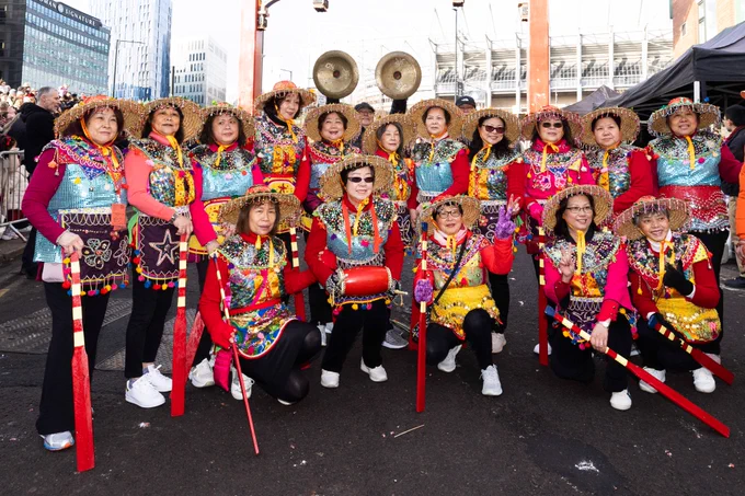A group of ladies in traditional Chinese attire standing under the Chinese arch on Stowell Street.