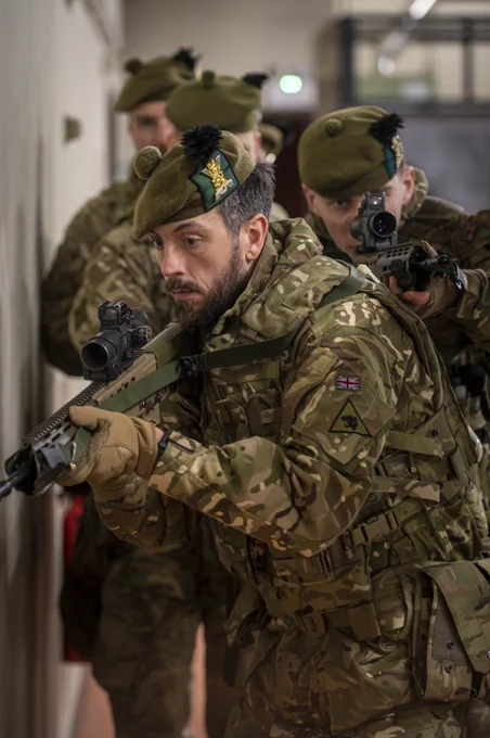 Two soldiers in uniform are pictured with their weapons drawn.