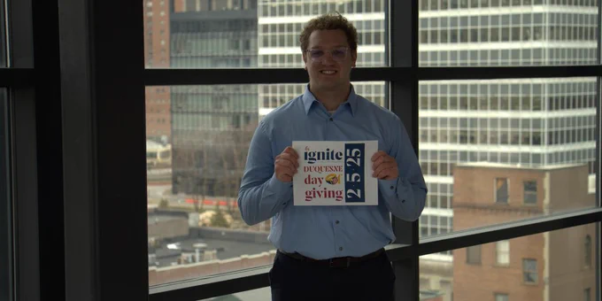 Student holding Duquesne Day of Giving sign.