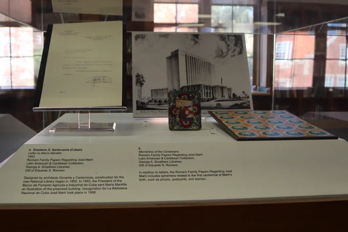 An exhibit case containing signed correspondence, a photo in a small picture frame, and a photo of a large government building.