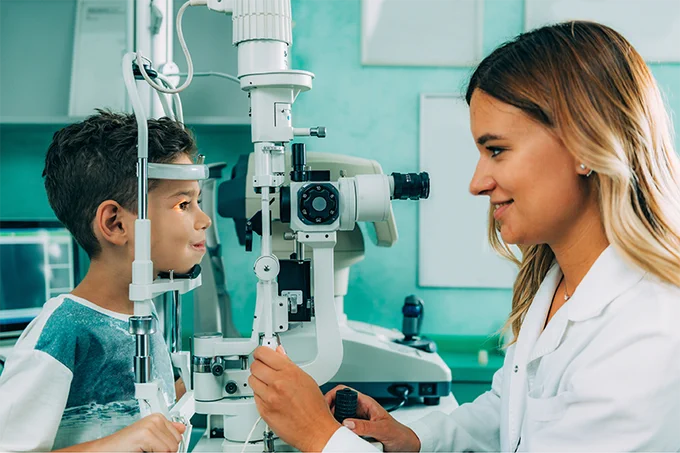 Young Asian boy having his eyesight checked by a female optometrist in a clinic.
