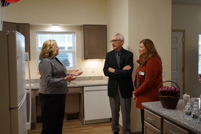 Secretary Kathy Blumenfeld, Governor Tony Evers, and Donna Braun, Executive Director of Dodge County Housing Authority talking in kitchen area in one of Dodge County Housing Authority's affordable housing units in the City of Juneau.