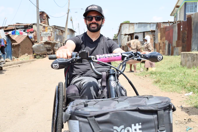 A man wearing sunglasses and a MATT cap using a third-wheel device with a MATT-branded handlebar bag.