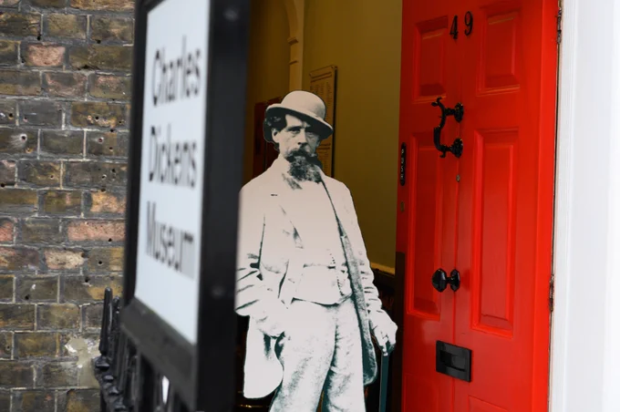 A close-up of the Museum’s red font door, with a cardboard cut-out of Charles Dickens standing in the open doorway.