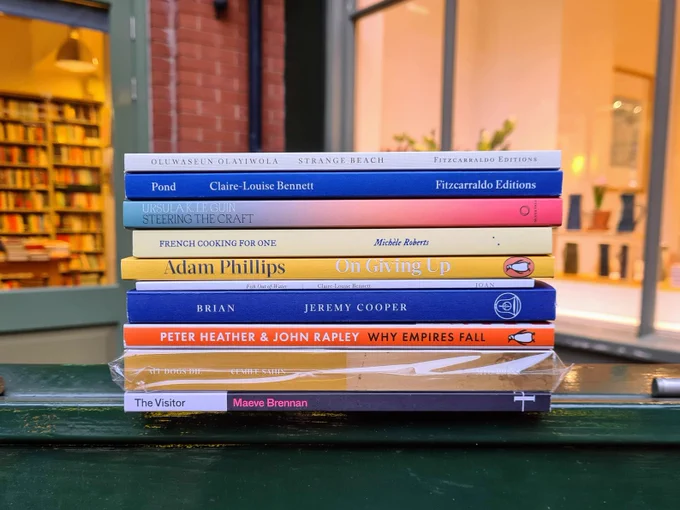 The top ten bestselling books last week at the London Review Bookshop, photographed outside the shop in a pile, spine-on. From the top:

1. STRANGE BEACH by Oluwaseun Olayiwola
2. POND by Claire-Louise Bennett
3. STEERING THE CRAFT by Ursula K. Le Guin
4. FRENCH COOKING FOR ONE by Michèle Roberts
5. ON GIVING UP by Adam Phillips
6. FISH OUT OF WATER by Claire-Louise Bennett
7. BRIAN by Jeremy Cooper
8. WHY EMPIRES FALL by Peter Heather & John Rapley
9. ALL DOGS DIE by Cemile Sahin, tr. Ayça Türkoğlu
10. THE VISITOR by Maeve Brennan