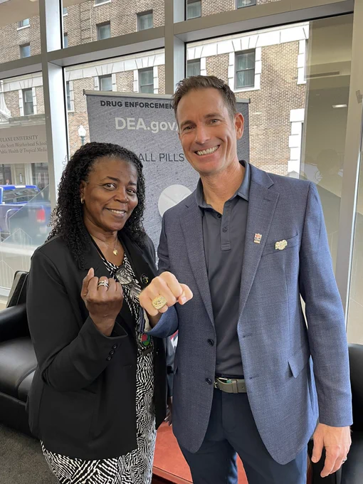 Two people stand together and show their rings. One person is wearing a Super Bowl championship ring.