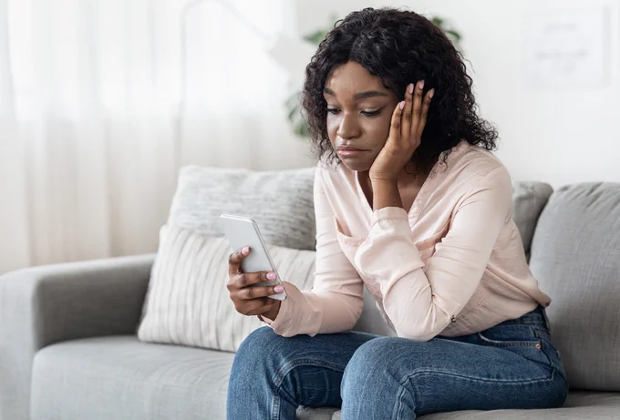 Photo of a woman looking dejectedly at her phone