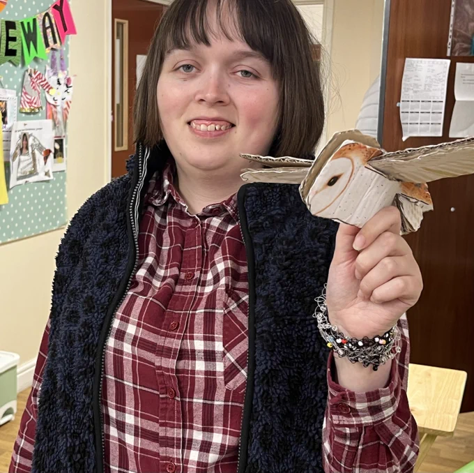 A woman who attends Reading Mencap's day service is showing off a bird she made out of cardboard.