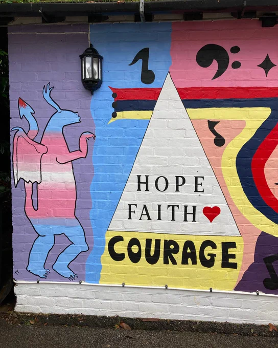 image of a wall painted with the writing ' Hope Faith Courage' with a red heart next to it. Musical notes and colourful patterns surround the writing.