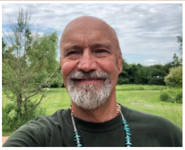 Sky Otter smiling and wearing turquoise bead necklace with nature background.