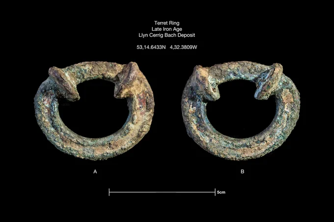 A metal ring with two pieces of metal passing through the top of the ring is shown on a black background. 