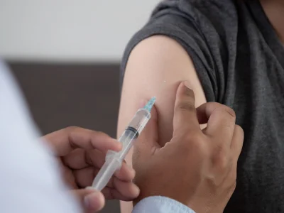 A healthcare worker administers a vaccine to a person's upper arm.
