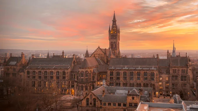 University of Glasgow main building with sunset sky of yellow and orange hues. 