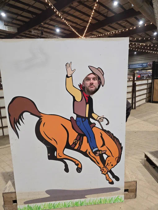 A person poking their head through a hole to appear as a cowboy riding a horse