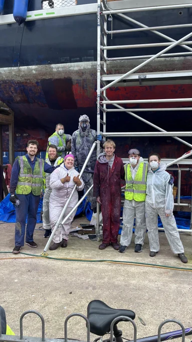 A team of workers next to Prolific's hull and a scaffolding tower