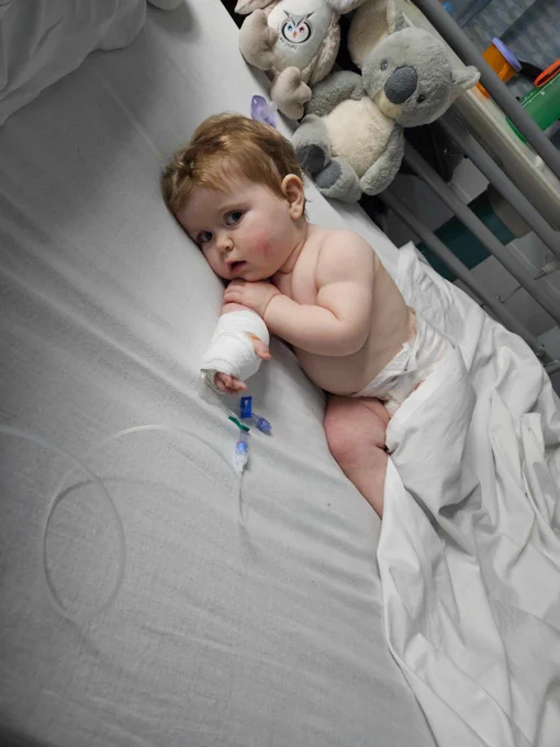 A photo of a poorly Annabell on a hospital bed, with a bandage on her arm.