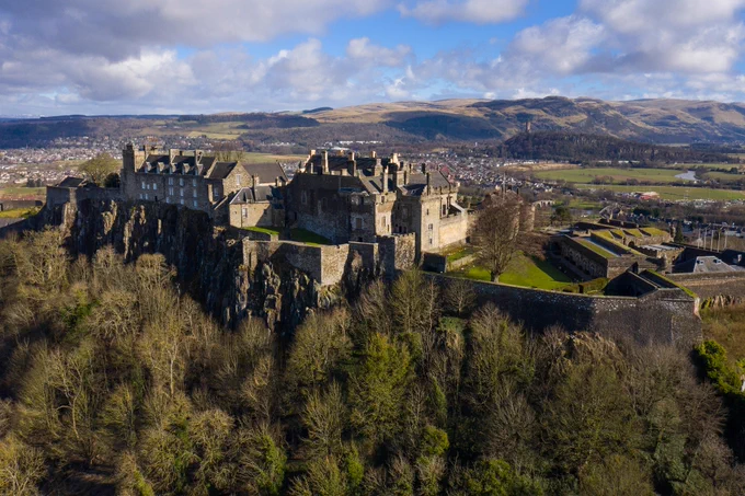 View of castle on hill with hills and clouds in the background