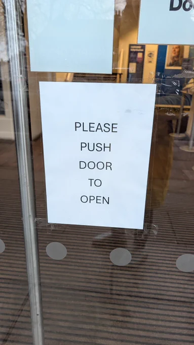 Photo of broken automatic door at Halifax bank entrance with sign taped to door reading "Please push door to open"