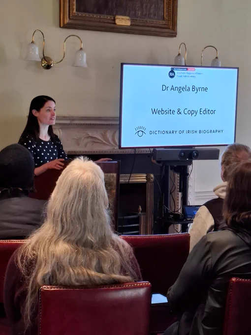 Angela Byrne speaking to the group using the screen that has some text on it