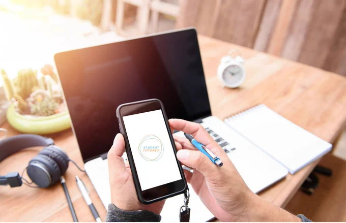 Image shows someone looking at their smartphone. The Student Futures logo is on the smartphone screen.