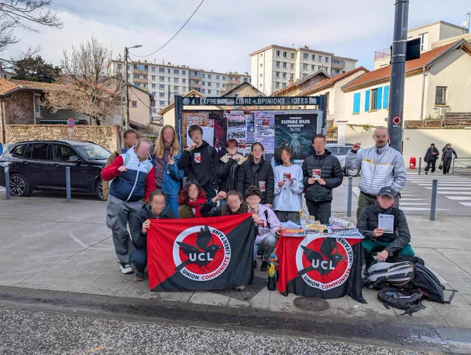 Photo des camarades posant ensemble, autour de la table de presse de l'UCL.
On voit deux drapeaux rouge et noir de l'UCL et 14 camarades dont des lycéennes et lycéens !